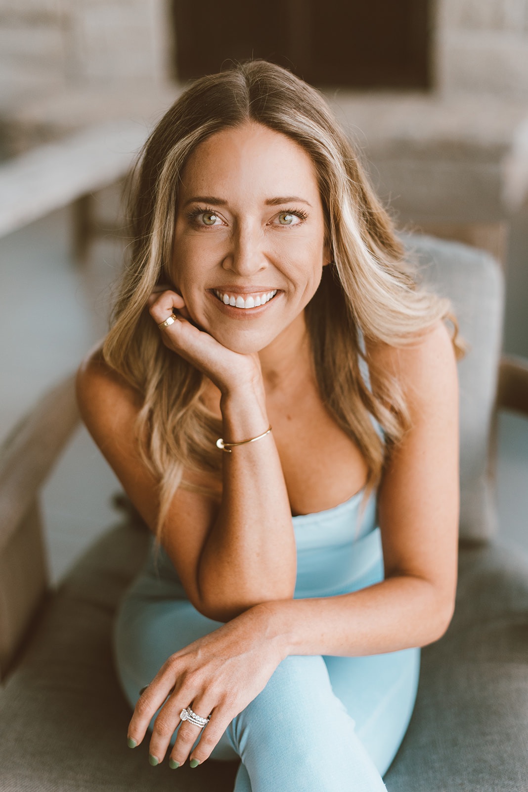 happy blonde woman sitting in aliving room looking up